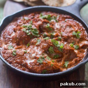 The healthier version of Chicken Tikka Masala garnished with coriander in a pan.