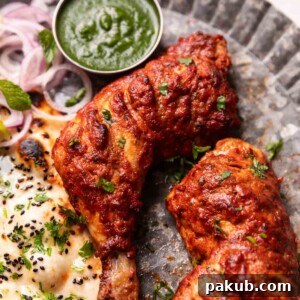tandoori chicken served on a plate with naan, chutney, and sliced onions