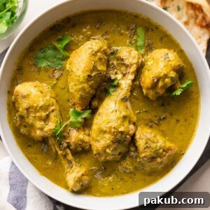 Picture of saag chicken served in a white bowl with naan on the side