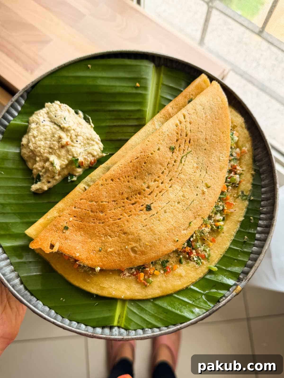 Protein-Packed Moong Dal Chilla with Savory Filling 2 Stuffed Moong Dal Chilla served with chutney on the side on a banana leaf plate