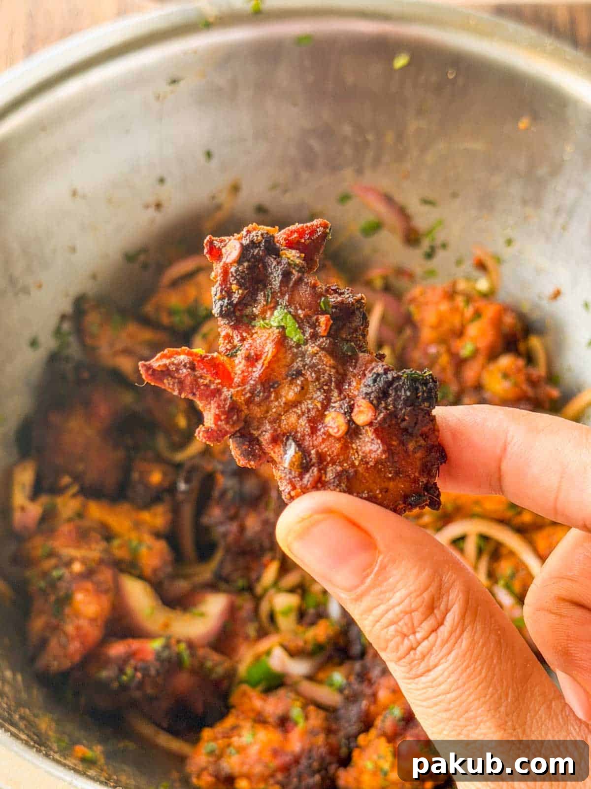 Air Fryer Chatpata Chicken Bites: Crisp Tangy Flavor 4 an image of a person holding a chicken bite to showcase its color and texture