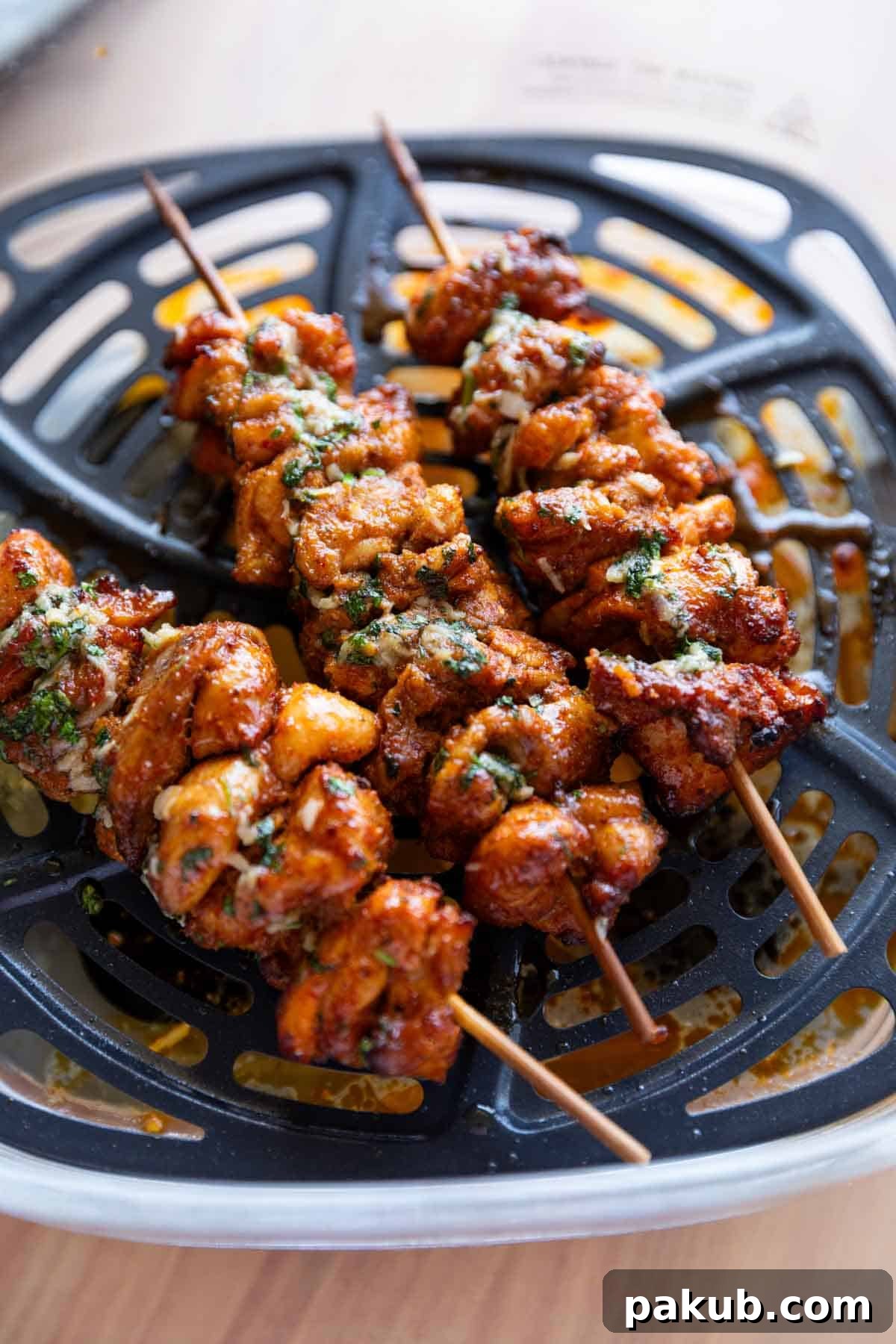 a close up image of achari chicken tikkas in the air fryer they were cooked in