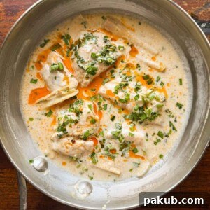thai poached fish in coconut milk topped with chilli oil and spring onions served in a pan