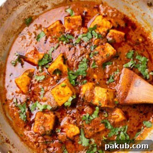 Dhaba style paneer masala in a kadhai with a wooden ladle
