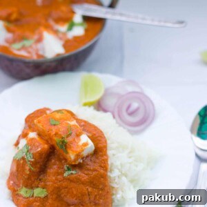 Healthy Paneer Makhani garnished with coriander and served with rice and a side of chopped onions in a white plate.