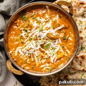 Picture of paneer lababdar served in a copper kadhai with naan on the side