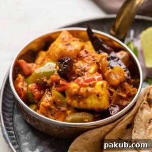 Achari Paneer served in a copper steel bowl with rotis on the side