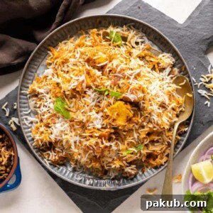 Paneer Biryani served on a grey plate with fried onions on the side