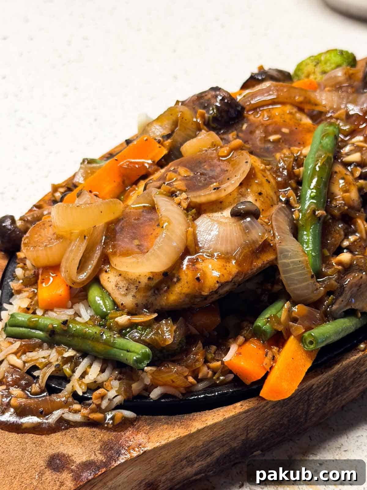a close up image of chicken sizzler served n a sizzling tray ready to eat