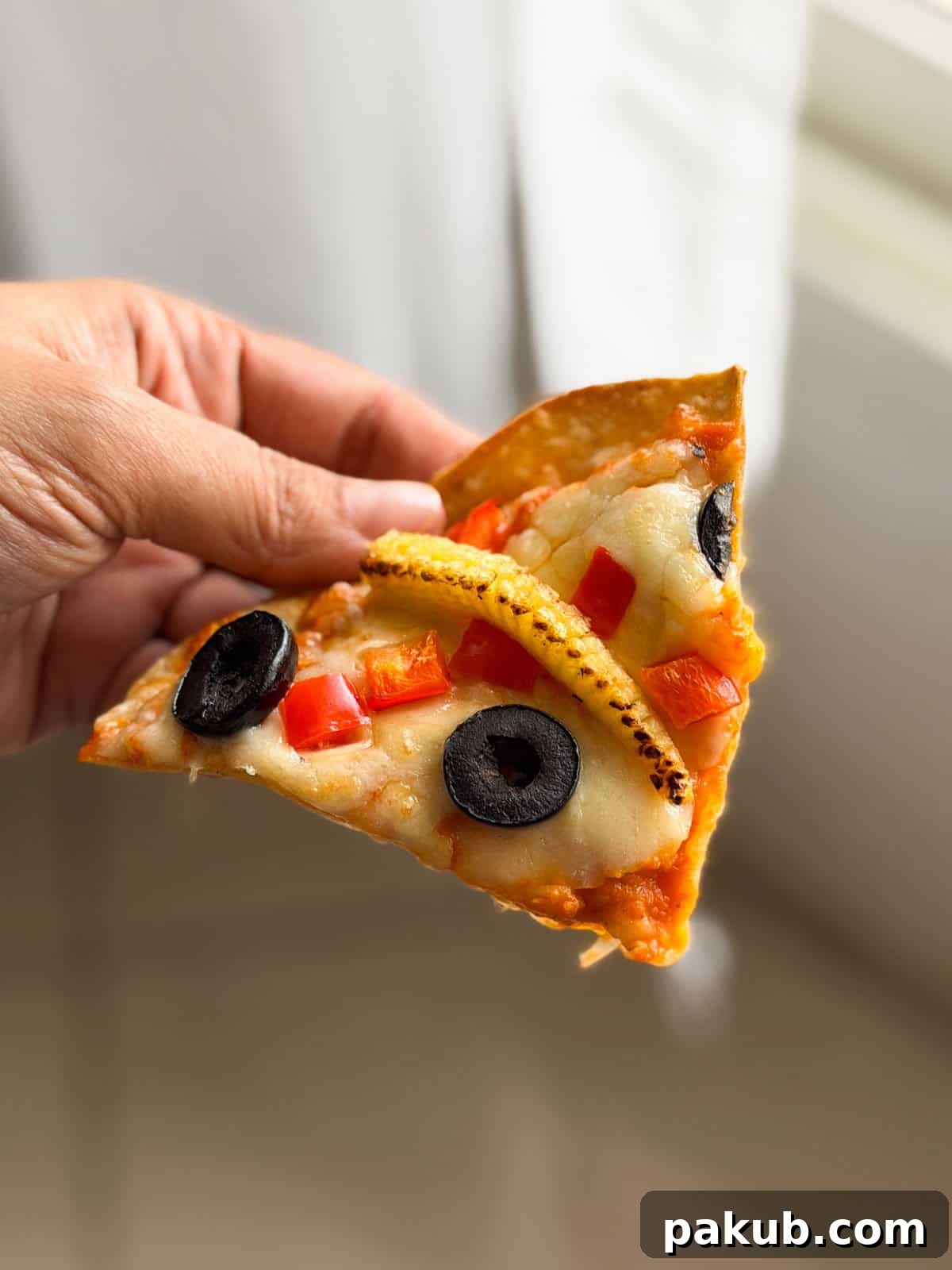 a person holding a slice of air fryer roti pizza