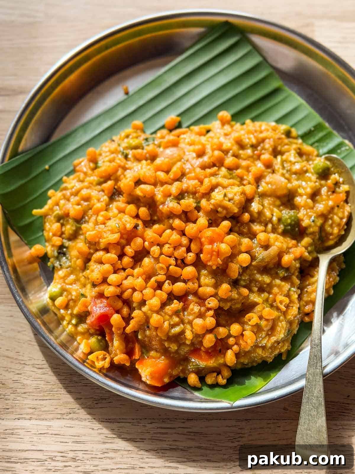 Bisi Bele Bath Recipe: Authentic Karnataka Lentil Rice 3 bisi bele bath topped with boondi and served on a plate lined with banana leaf