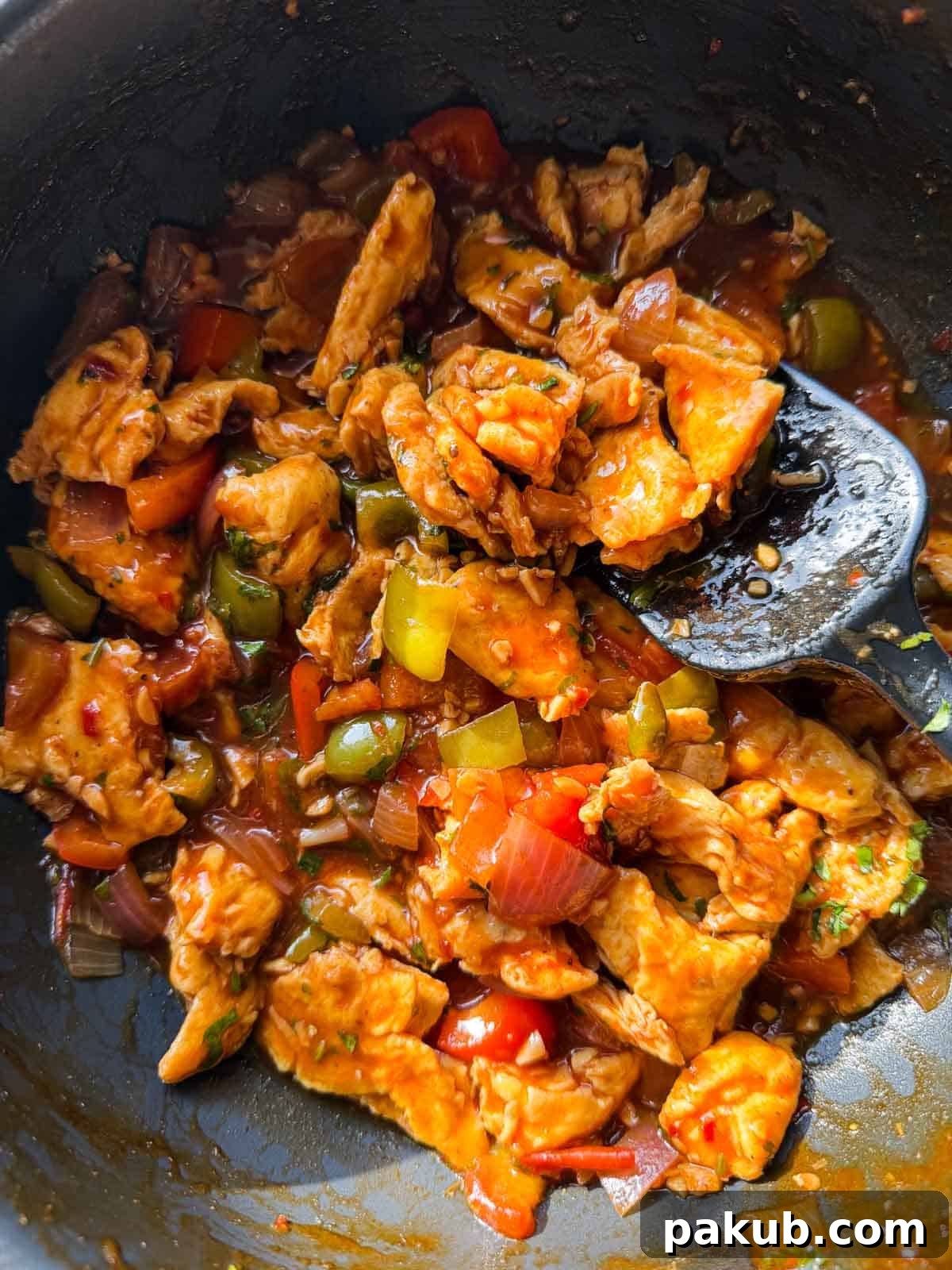 chilli egg stir fry in its cooking pan with ladle