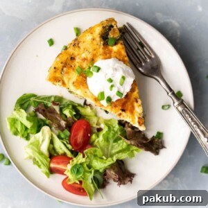 A slice of spinach potato veggie frittata topped with a dollop of sour cream and chopped green onions