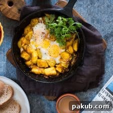 Spiced Indian Potatoes and Egg cooked in a skillet and garnished with coriander.
