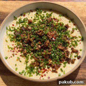 an image of chinese steamed eggs garnished with mushroom and spring onion ready to be eaten