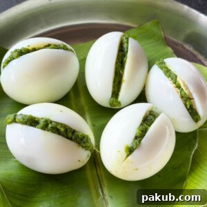 stuffed eggs served on a steel plate covered with banana leaf