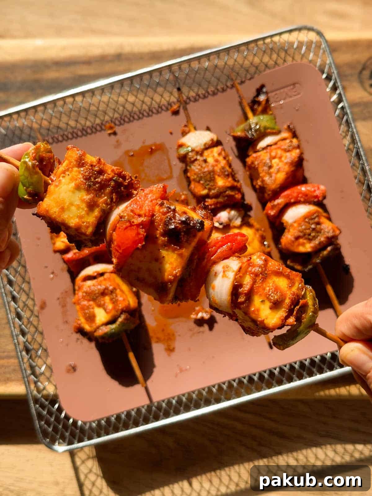 Crispy Air Fryer Paneer Tikka Recipe 2 a person holding a skewer of air fryer paneer tikka to showcase its color and texture