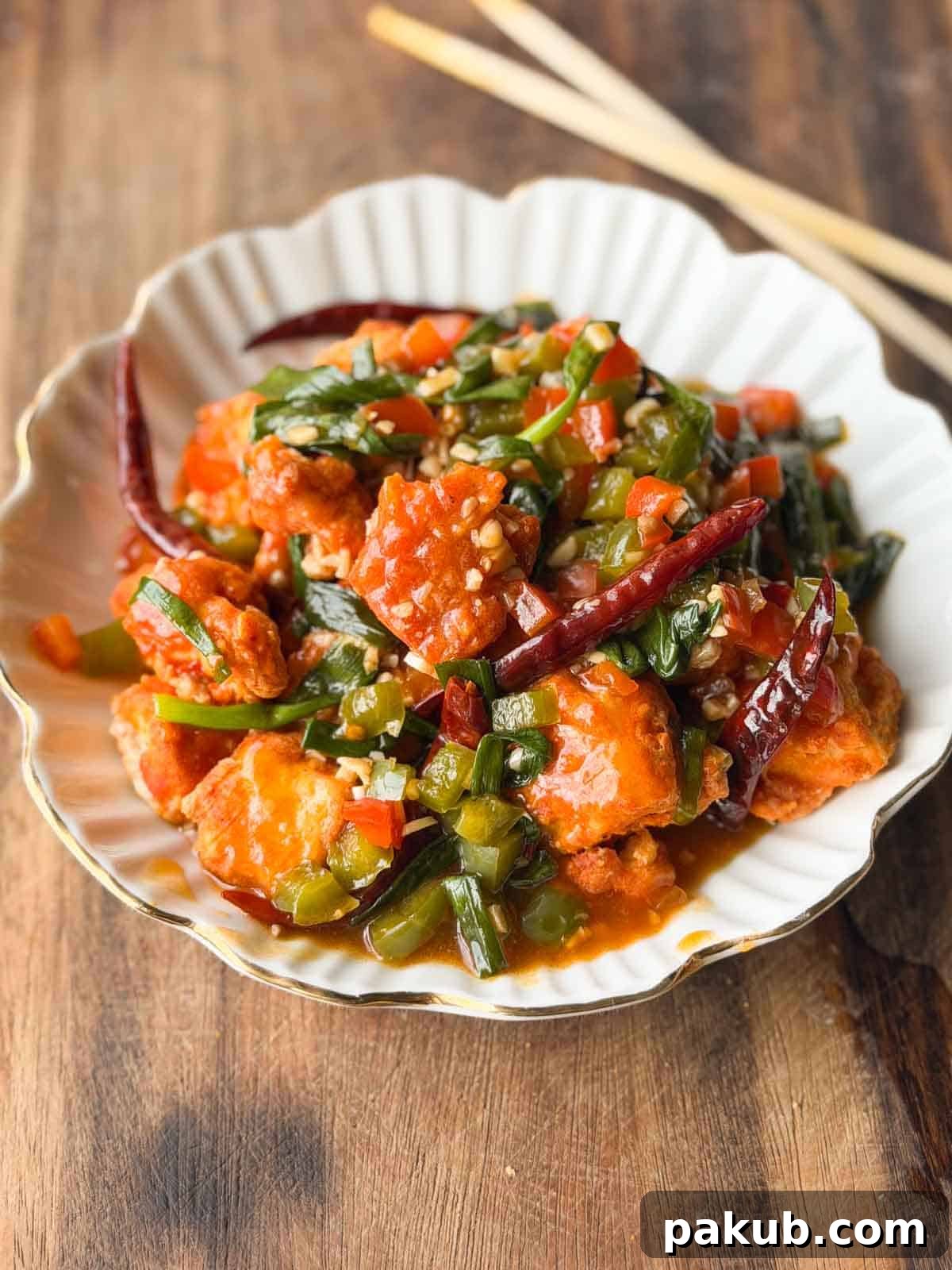 crispy chili tofu served in a white bowl with chopsticks
